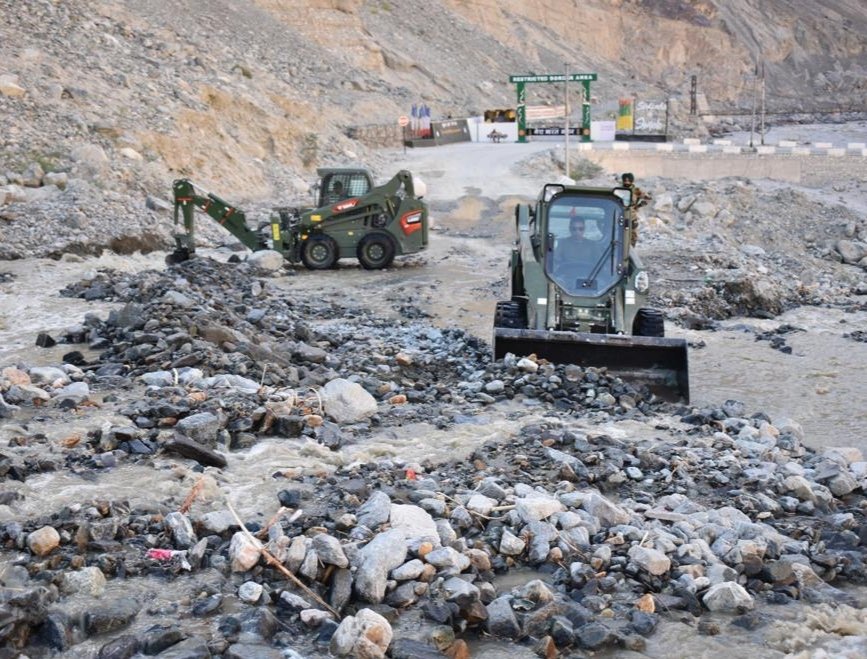 Men and machines of the Army clearing boulders from the road