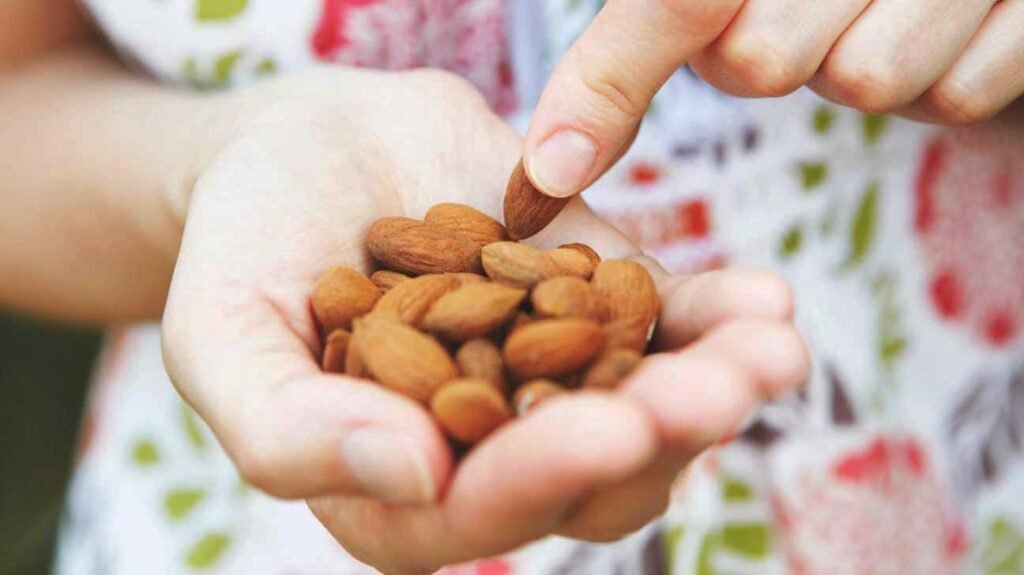 woman holding almonds in palm of hand 1296x728 1